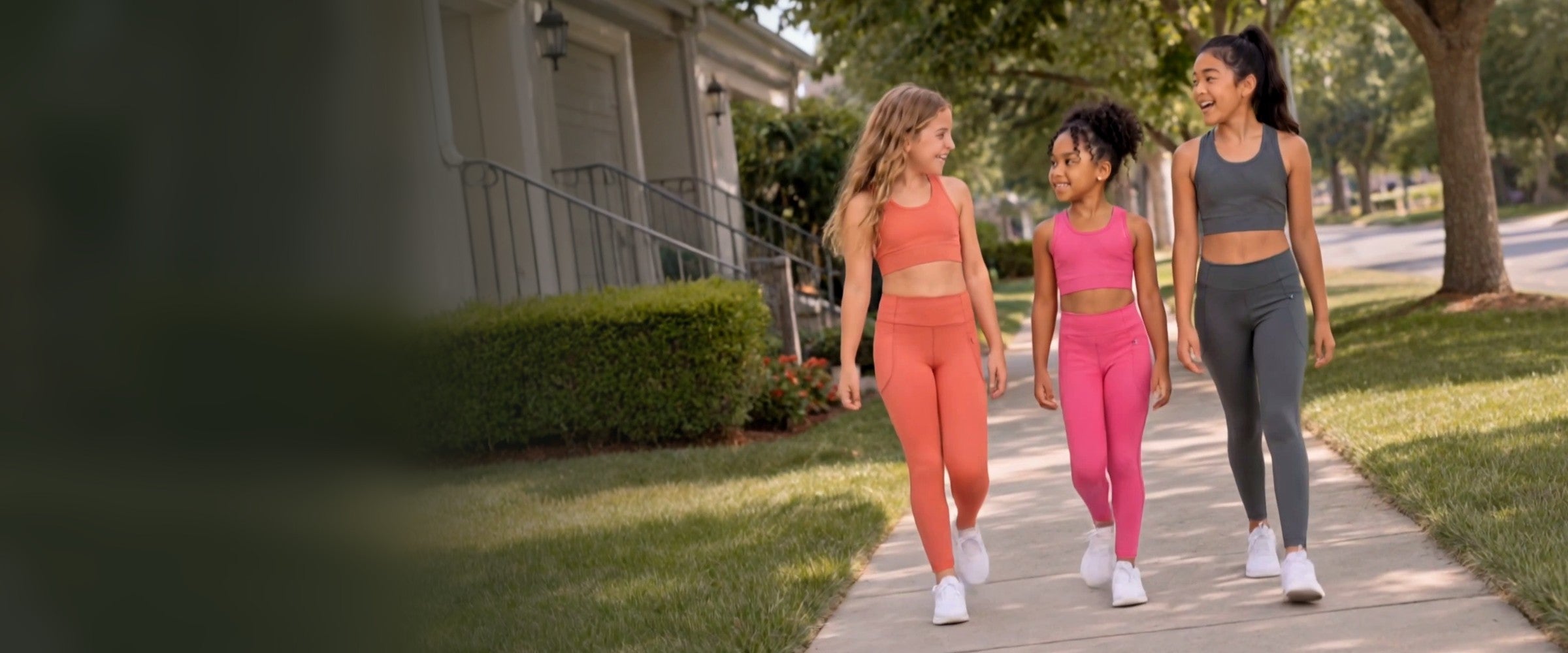 Three girls walking down a sunny sidewalk in Essenclo high-waisted leggings in coral, hot pink and grey