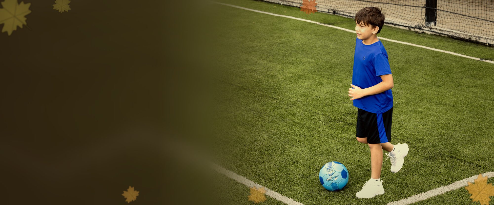 Boy in an Essenclo tee and shorts with a soccer ball on the field